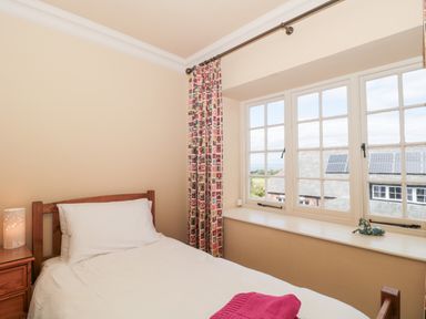 A bedroom with a single bed bedside table and a window showing rooftops at The Pound in Porlock