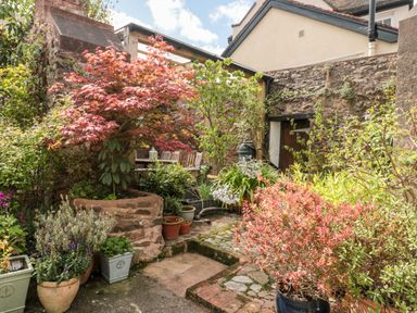 A garden area with various potted plants and shrubs surrounded by stone walls at The Pound in Porlock