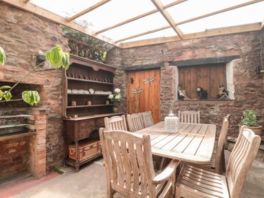 A dining area with wooden table and chairs stone walls and a wooden cabinet at The Pound in Porlock