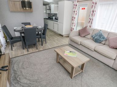 A living room with a sofa and coffee table next to a dining table and kitchen at Seahorse Retreat in Little Haven near Broad Haven