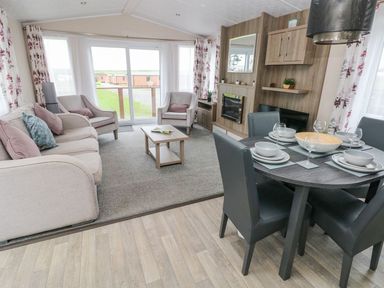 A living room with sofa chairs coffee table and dining table set at Seahorse Retreat Little Haven near Broad Haven