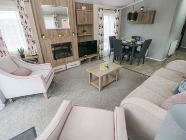 A living room with chairs a sofa coffee table dining table and TV at Seahorse Retreat in Little Haven near Broad Haven