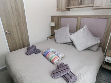 A bedroom with a double bed pillows and rolled towels on the bed at Seahorse Retreat in Little Haven near Broad Haven