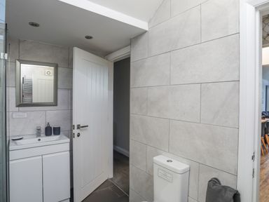 A bathroom with a sink cabinet mirror open door and toilet at Haulfryn in Moelfre