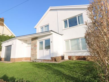 A house with white walls green lawn and leafless tree at 30 Long Shepherds Drive in Newton near The Mumbles