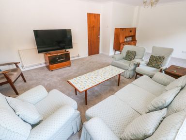 A living room with armchairs sofa coffee table television and wooden cabinet at 30 Long Shepherds Drive in Newton near The Mumbles