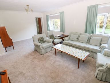 A living room with pastel upholstered sofa and armchairs a wooden coffee table and side table at 30 Long Shepherds Drive in Newton near The Mumbles