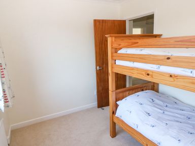 A bedroom with a wooden bunk bed and nautical patterned bedding at 30 Long Shepherds Drive in Newton near The Mumbles