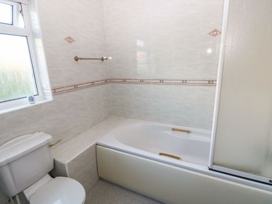 A bathroom with a bathtub a toilet and a window at 30 Long Shepherds Drive in Newton near The Mumbles
