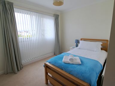 A bedroom with a bed and a bedside table at 30 Long Shepherds Drive in Newton near The Mumbles