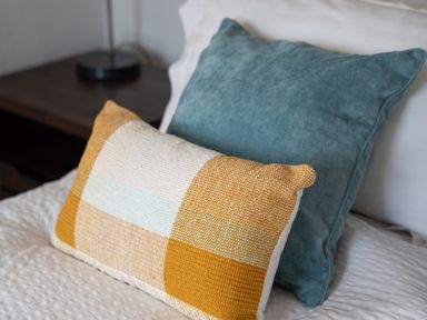 Two pillows on a white bed with a bedside table and lamp in the background at The Rum House in Porthallow