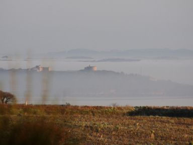 A landscape view of a field with distant hills and buildings in the background