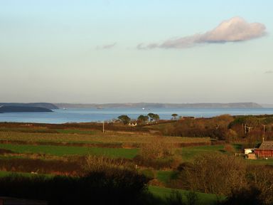 A coastal landscape with fields and trees overlooking the sea at The Rum House in Porthallow