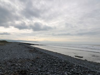 A rocky beach with waves and cloudy sky at Gwent 74 in Borth