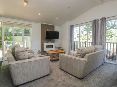 A living room with sofas and a television at Treetops, Beech Hill 13, Fallbarrow Park near Bowness-On-Windermere