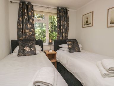 A bedroom with two beds and a window at Treetops, Beech Hill 13, Fallbarrow Park near Bowness-On-Windermere