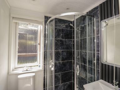 A bathroom with a shower, toilet, sink, and window at Treetops Beech Hill 13 ,Fallbarrow Park near Bowness-On-Windermere