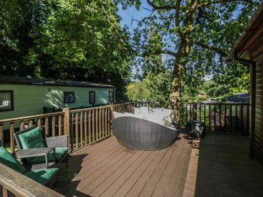 A decking area with seating and trees at Treetops Beech Hill 13, Fallbarrow Park near Bowness-On-Windermere