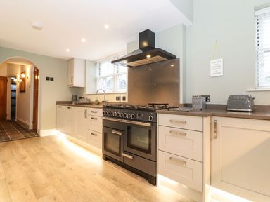 A kitchen with a stove oven dishwasher toaster and cabinets at Blencathra in Keswick