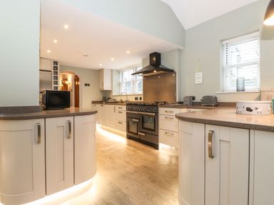 A kitchen with cabinetry countertops a stove and windows at Blencathra in Keswick