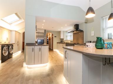 A kitchen with cabinets, a washing machine and dryer, a refrigerator, a stove, and a countertop with a green pitcher at Blencathra in Keswick