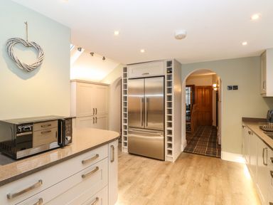 A kitchen with a double door refrigerator a microwave on the counter and an arched doorway leading to another room at Blencathra in Keswick