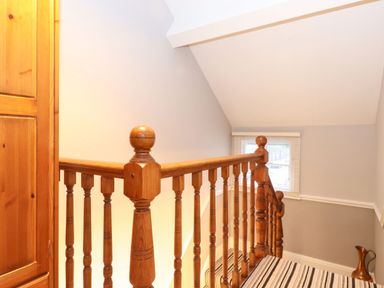 A wooden staircase railing with spindles and a window with blinds at Blencathra in Keswick