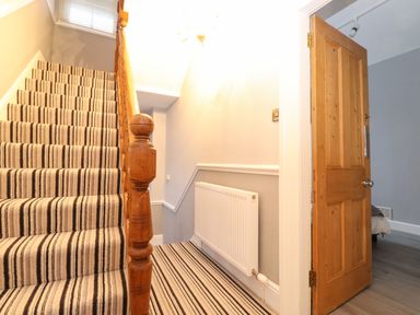 A staircase with striped carpet next to a wooden door leading to a room with grey walls at Blencathra in Keswick