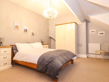 A bedroom with a bed and bedside tables a wardrobe and a chair at Blencathra in Keswick