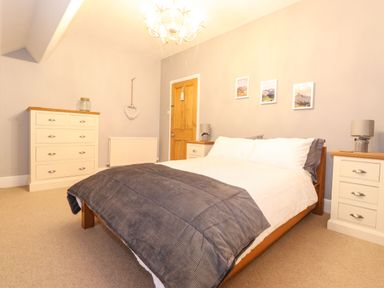 A bedroom with a double bed two bedside tables a chest of drawers and pictures on the wall at Blencathra in Keswick