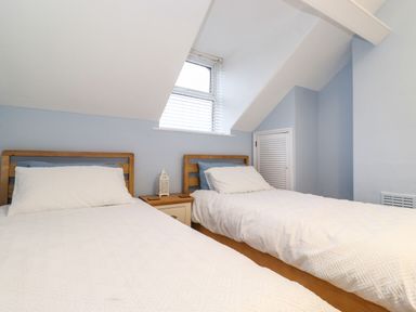 A bedroom with two single beds a nightstand and a window with blinds at Blencathra in Keswick