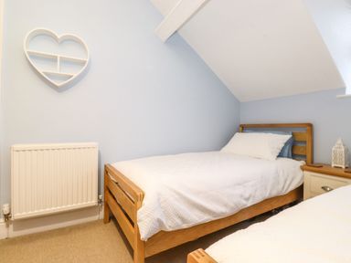 A bedroom with two single beds wooden frames and a heart shaped wall shelf at Blencathra in Keswick