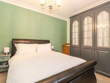 A bedroom with a bed two bedside tables with lamps and a large wardrobe with glass doors at Blencathra in Keswick