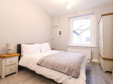 A bedroom with a bed bedside tables with lamps a window and a wardrobe at Blencathra in Keswick