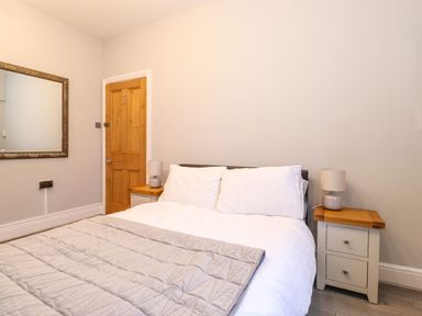 A bedroom with a bed, two bedside tables with lamps, and a wooden door at Blencathra in Keswick