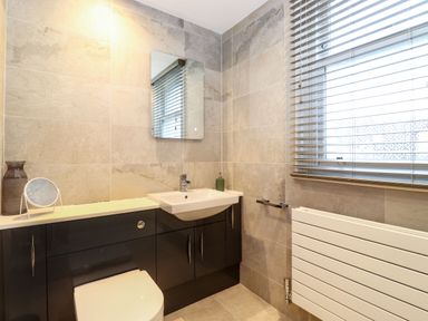 A bathroom with a toilet sink mirror window and radiator at Blencathra in Keswick
