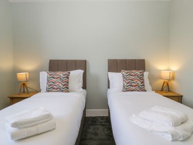 A bedroom with two single beds white linens and patterned pillows at Birch House in Corsham