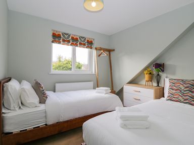 A bedroom with two single beds a chest of drawers and a window at Birch House in Corsham