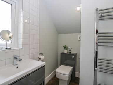 A bathroom with a sink, toilet, mirror, toilet paper holder, and a towel rack at Birch House in Corsham