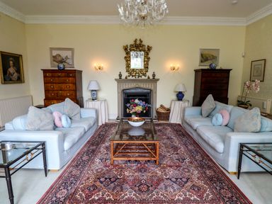 A living room with two sofas facing a fireplace with a mirror above at Craster Tower Penthouse Craster