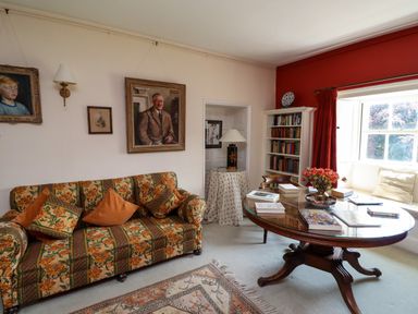 A sitting room with a floral sofa a wooden oval table and a bookshelf at Craster Tower Penthouse in Craster