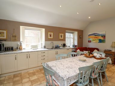 A kitchen with a marble countertop dining table with chairs and red sofa at Craster Tower Penthouse in Craster