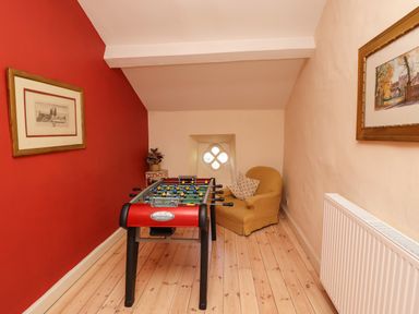 A game room with a foosball table an armchair paintings on walls and a radiator at Craster Tower Penthouse in Craster
