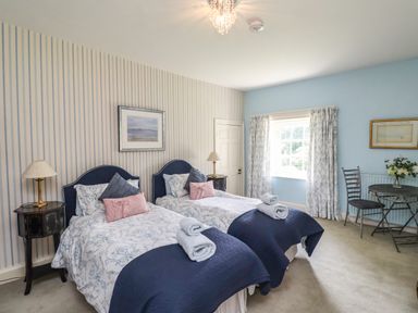 A bedroom with two single beds side by side a small table with two chairs and a window at Craster Tower Penthouse in Craster