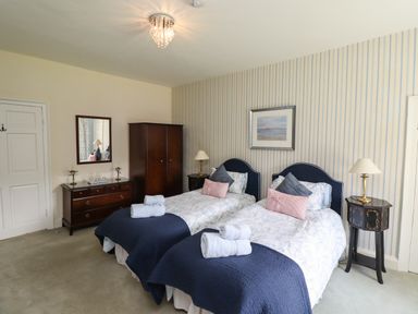 A bedroom with two single beds bedside tables dressers and a wardrobe at Craster Tower Penthouse in Craster