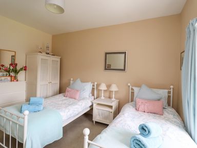 A bedroom with two single beds a white wardrobe a dresser with flowers and a small nightstand with lamps at Craster Tower Penthouse in Craster