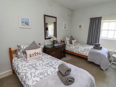 A bedroom with two single beds a chest of drawers and a window with curtains at Craster Tower Penthouse in Craster