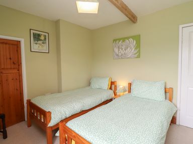 A bedroom with two wooden single beds with green patterned bedding at No2 Budle Bay Cottage Bamburgh