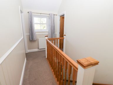 A hallway with a stair railing and window at Pippin in Lucker