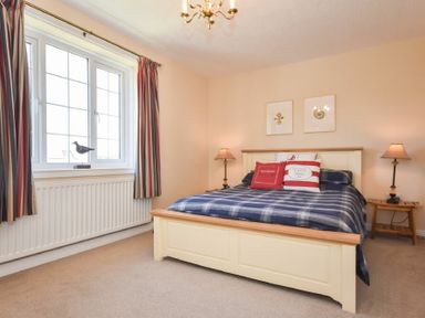 A bedroom with a bed with striped bedding two bedside tables with lamps and a window with striped curtains Inveray Seahouses